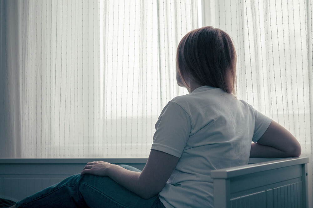 Eine Frau sitzt am Fenster und schaut in die Ferne